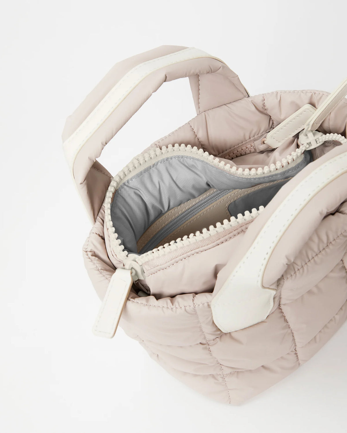 Open Vee Collective Porter Tote Bag Mini in Soft Taupe, showing the quilted exterior, top zipper, and interior compartments of the tote bag.