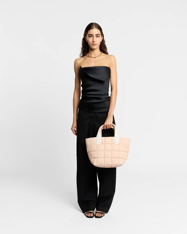 On-body picture of a woman holding the Small Porter Tote Bag in Cameo Rose by Vee Collective, wearing a minimalistic outfit against a clean studio background.