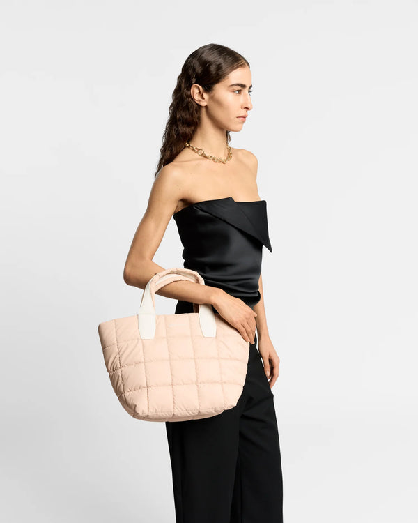 On-body picture of a woman carrying the Small Porter Tote Bag in Cameo Rose by Vee Collective, wearing a minimalistic outfit against a clean studio background.