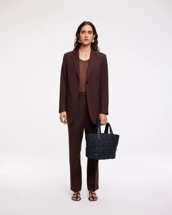 On-body picture of a woman carrying the Small Porter Tote Bag in Dark Navy by Vee Collective, wearing a minimalistic outfit against a clean studio background.