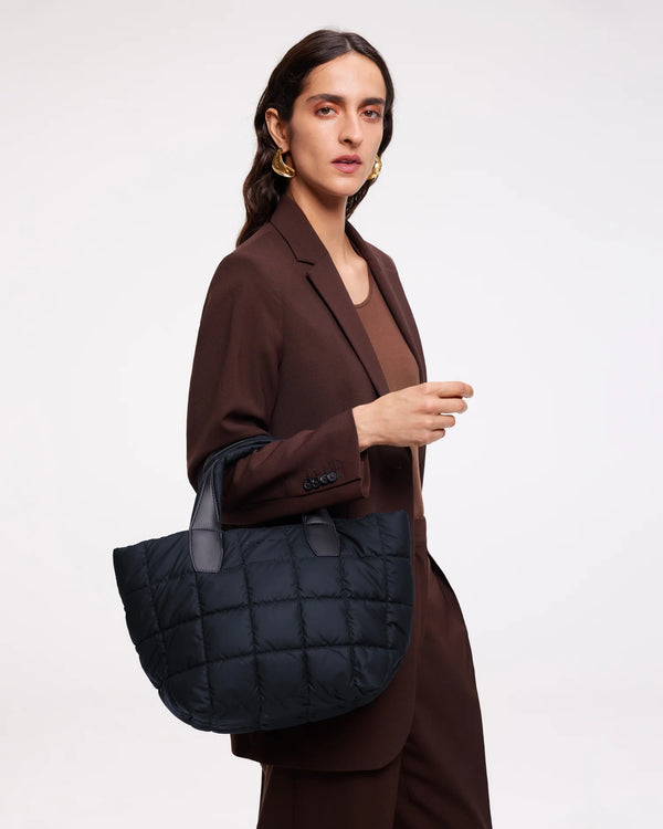 On-body picture of a woman holding the Small Porter Tote Bag in Dark Navy by Vee Collective, wearing a minimalistic outfit against a clean studio background.