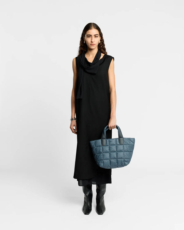 On-body picture of a woman holding the Small Porter Tote Bag in Pinstripe by Vee Collective, wearing a minimalistic outfit against a clean studio background.