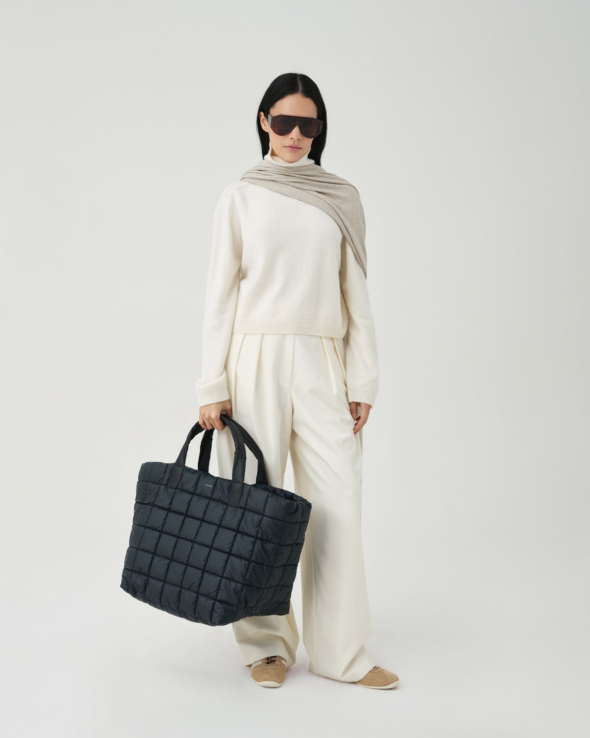 Model wearing a white outfit holding the porter weekender  bag on a white background