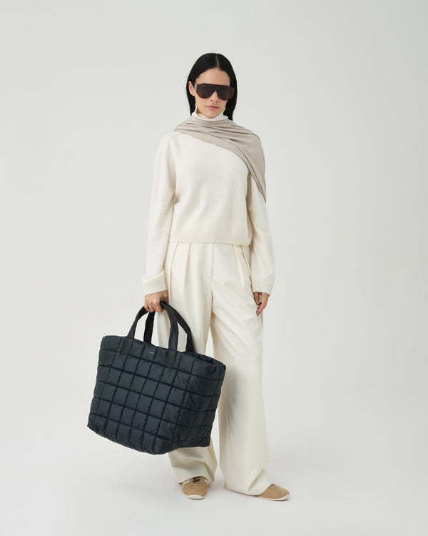 Model wearing a white outfit holding the porter weekender  bag on a white background