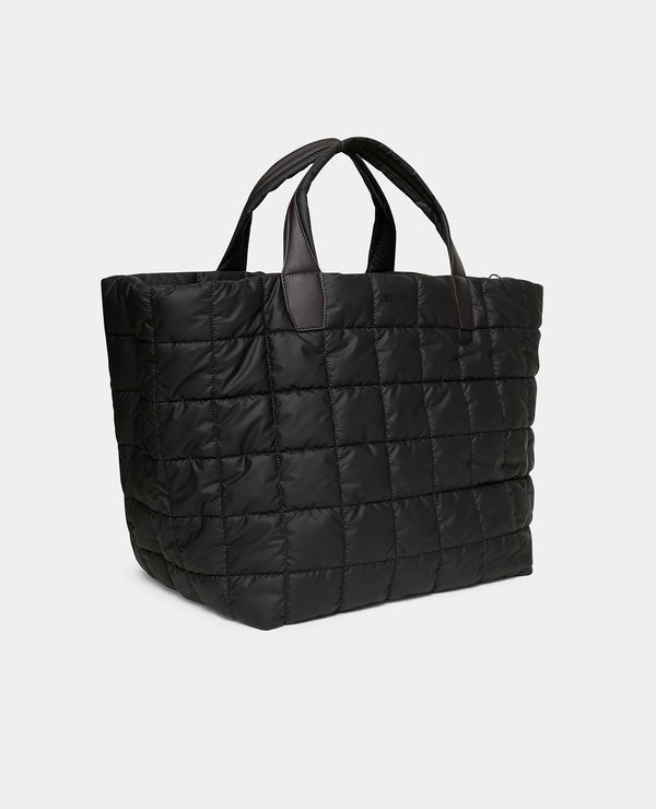 The  Porter weekender   espresso bag with brown handles, shown open and filled with travel items including a water bottle, cup, and small accessories. A plaid zip pouch and white sneakers are placed beside it on a white background.