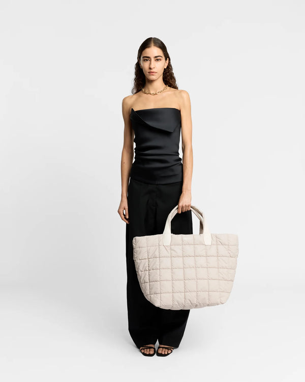 On-body picture of a woman carrying the Porter Weekender Tote Bag in Soft Taupe by Vee Collective, wearing a minimalistic outfit against a clean studio background.