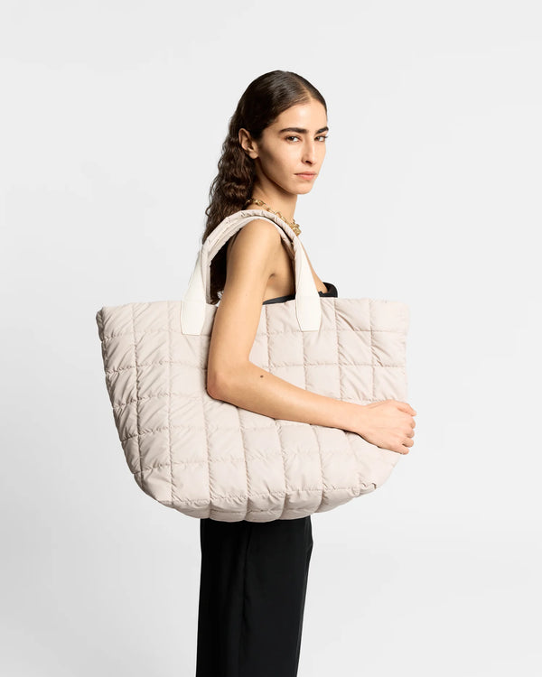 On-body picture of a woman carrying the Porter Weekender Tote Bag in Soft Taupe by Vee Collective, wearing a minimalistic outfit against a clean studio background.