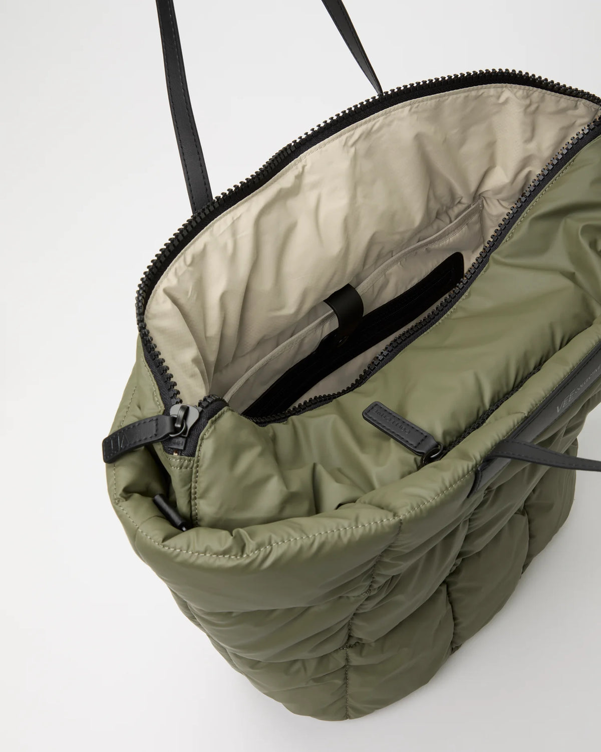 Open Vee Collective Porter Basque Bag in Moss, showing the quilted exterior, top zipper, and interior compartments of the tote bag.