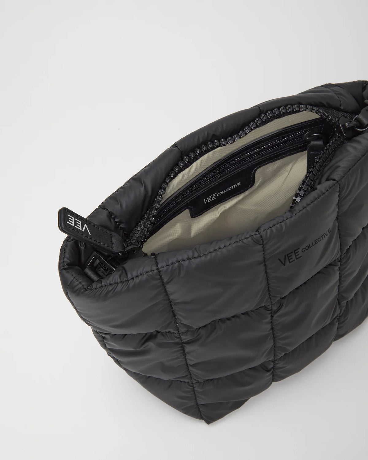 Open Vee Collective Porter Clutch Bag in Matt Black, showing the quilted exterior, top zipper, and interior compartments.