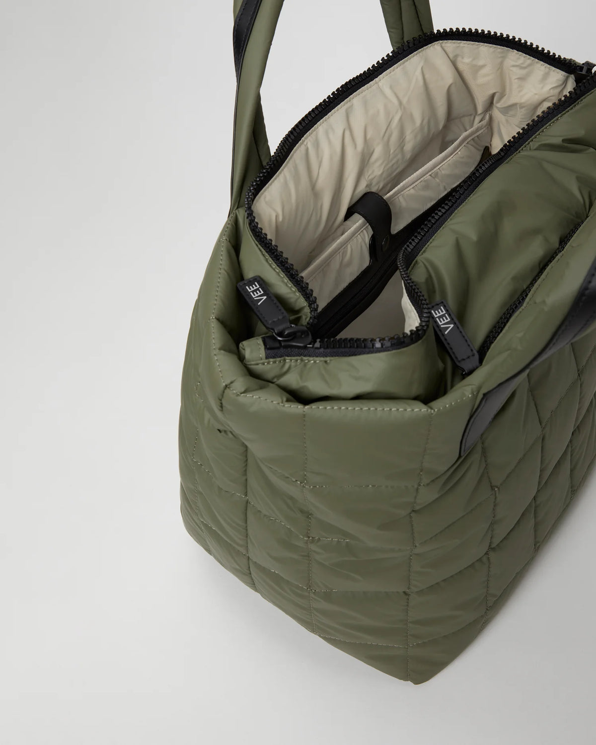 Open Vee Collective Porter Tote Medium in Moss, showing the quilted exterior, top zipper, and interior compartments of the tote bag.