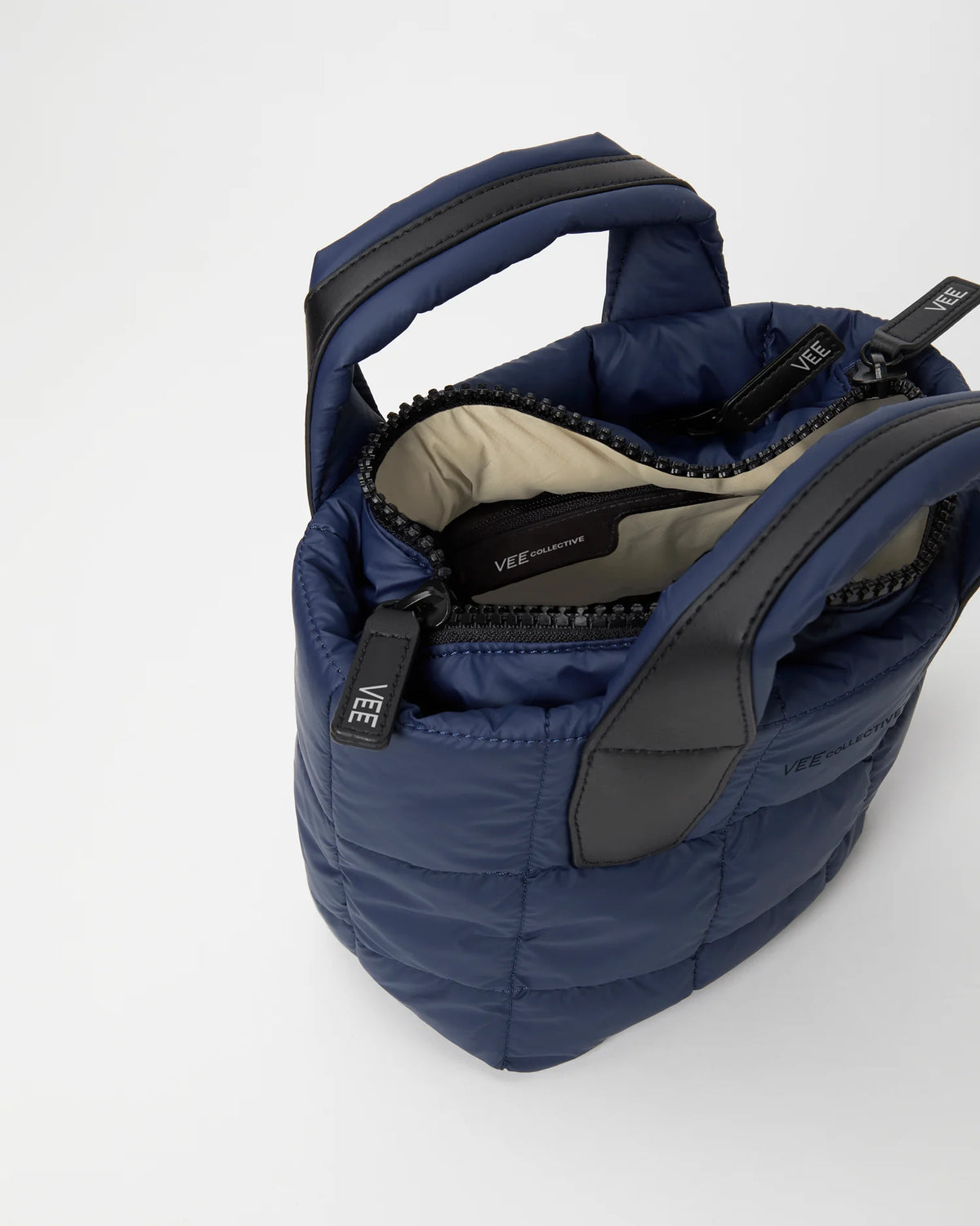 Open Vee Collective Porter Tote Mini in Deep Sea, showing the quilted exterior, top zipper, and interior compartments of the tote bag.
