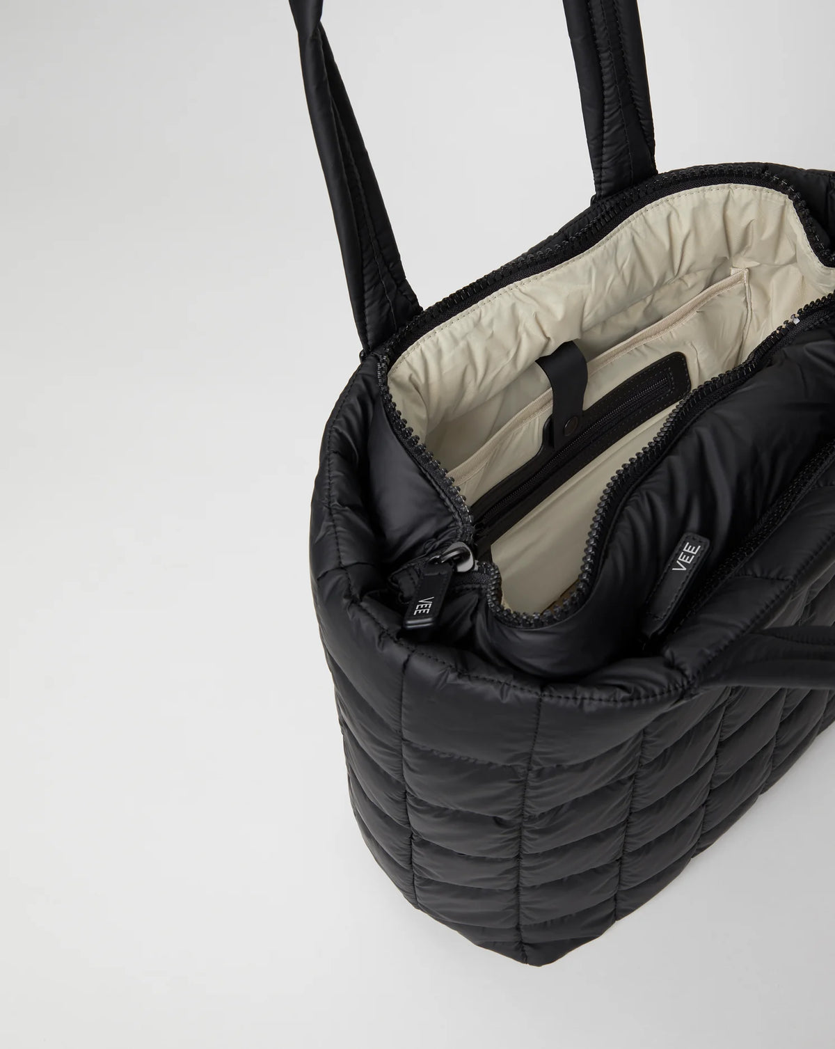 Open Vee Collective Porter Shopper Bagi in Matt Black, showing the quilted exterior, top zipper, and interior compartments of the tote bag.