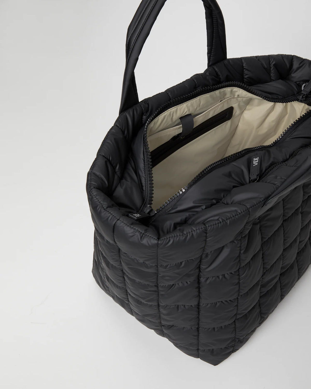Open Vee Collective Porter Weekender Bag in Matt Black, showing the quilted exterior, top zipper, and interior compartments of the tote bag.