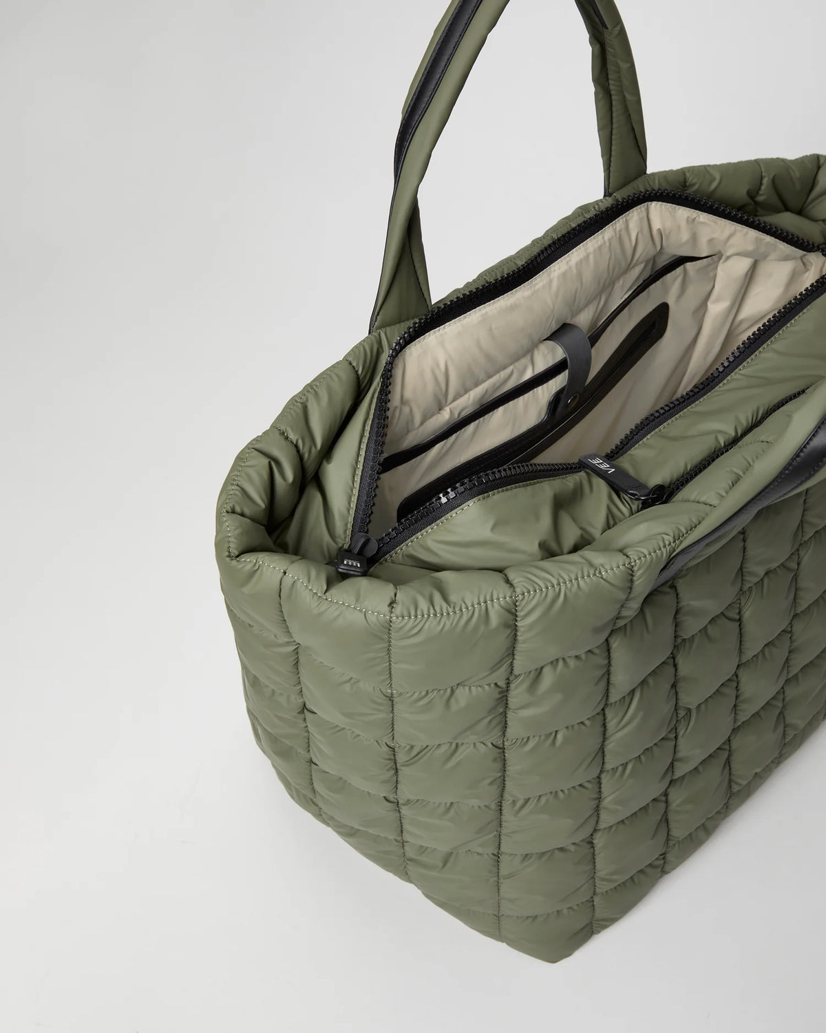 Open Vee Collective Porter Weekender Bag in Moss, showing the quilted exterior, top zipper, and interior compartments of the tote bag.