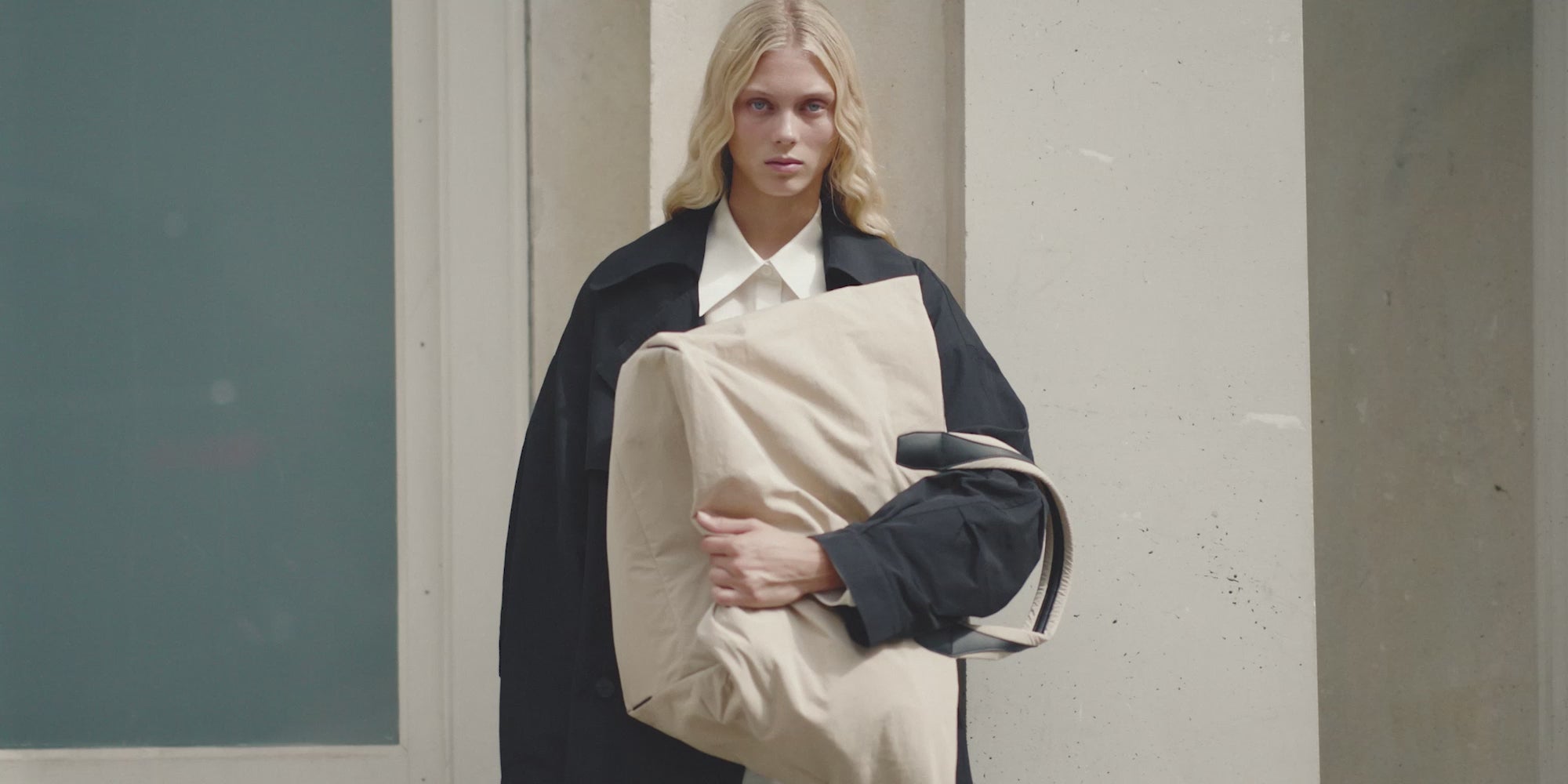 Video of a woman in a black trench coat carrying the Porter Essence MediumTote Bag in Beige Trench by Vee Collective.