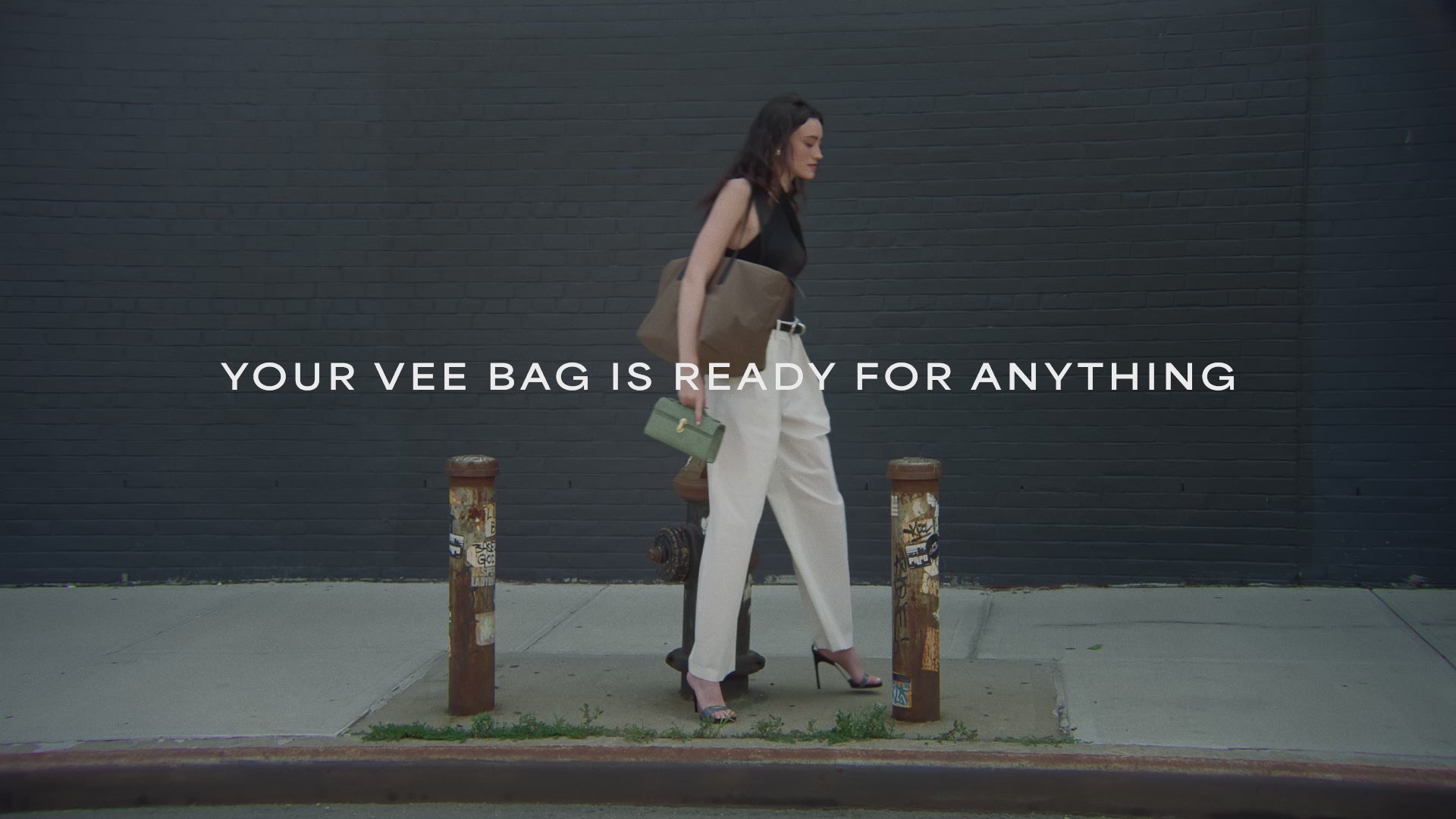 A video featuring a model wearing a sleeveless top and white trousers, carrying an Essence Medium Mink Bag while walking.