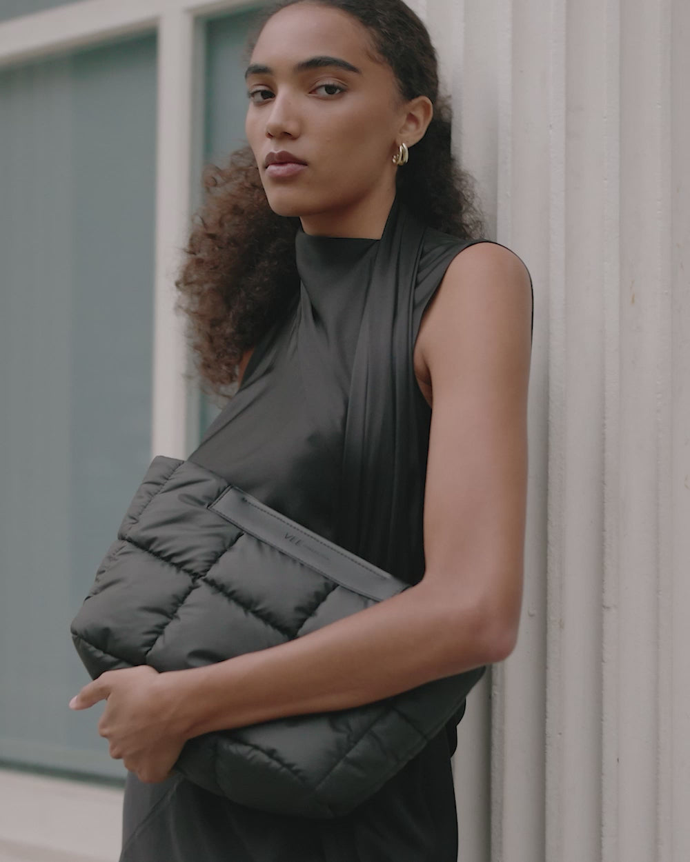 Close-up video of a woman wearing the VEE COLLECTIVE Porter Basque Clutch in Matt Black.