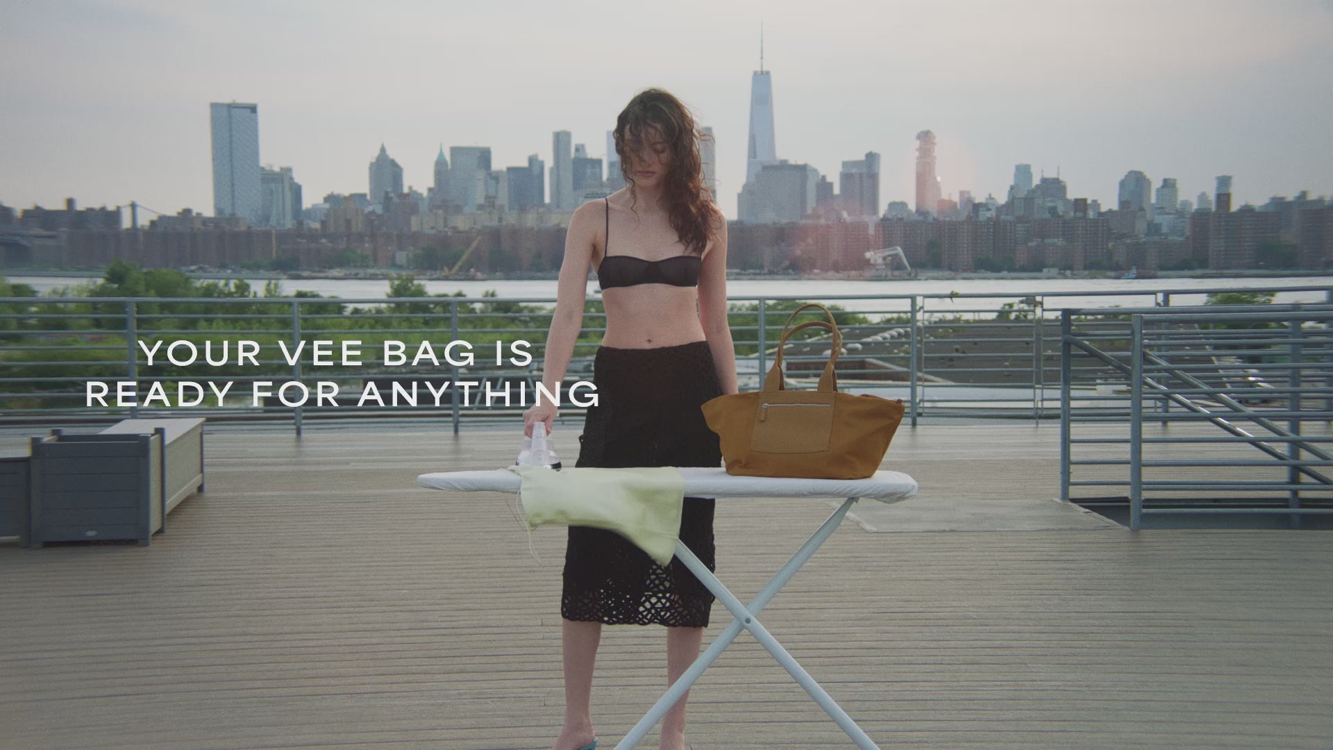 A video featuring a model ironing outdoors, with the Duo Tote Bag in amber placed on the ironing table.
