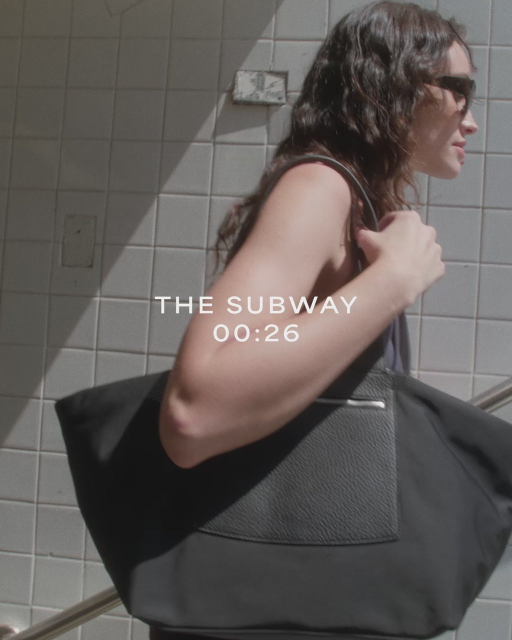 A woman with brown hair waking with the duo tote black bag