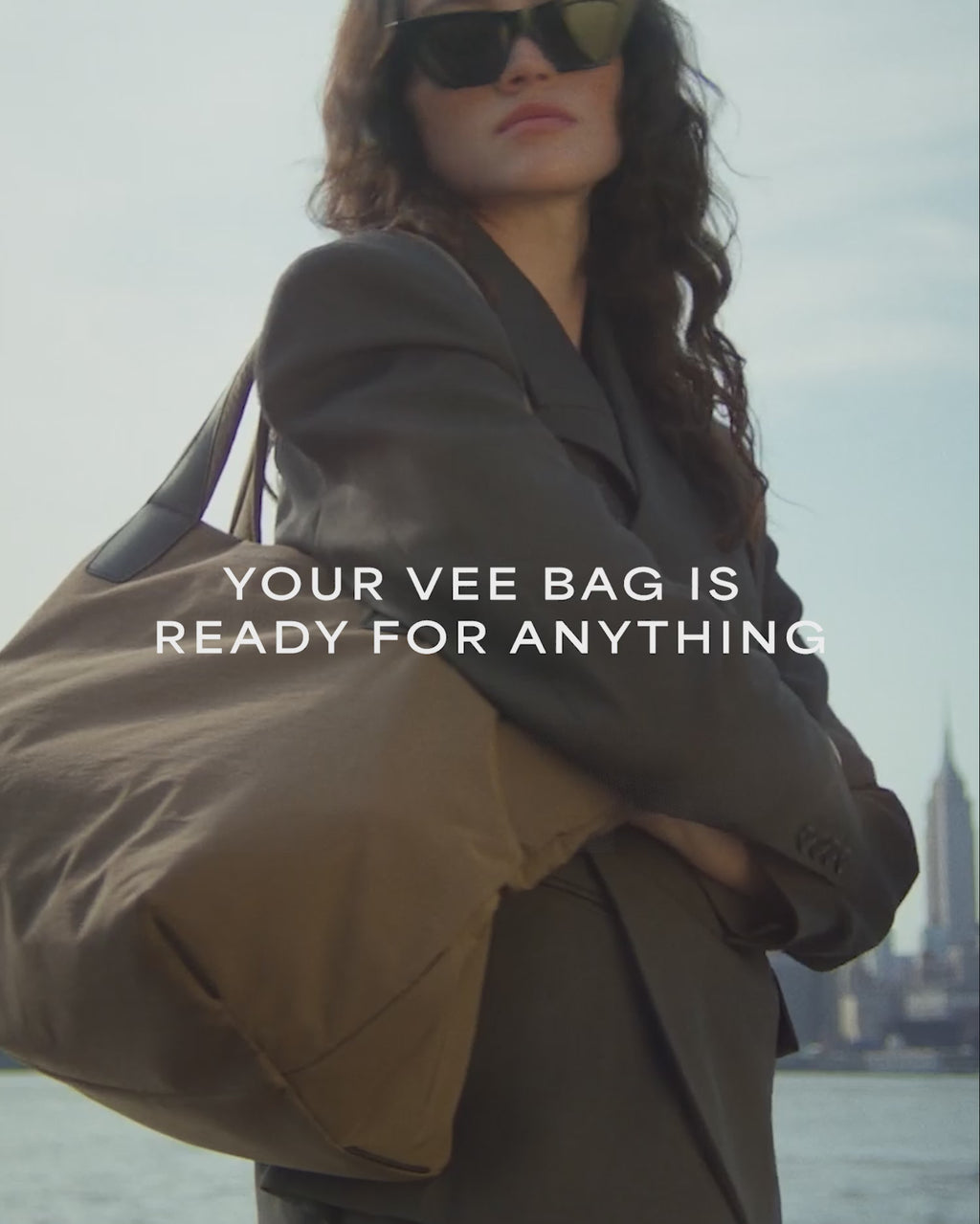 A video featuring a model wearing black sunglasses and a jacket, carrying an Essence Medium Mink Bag while standing in the city.