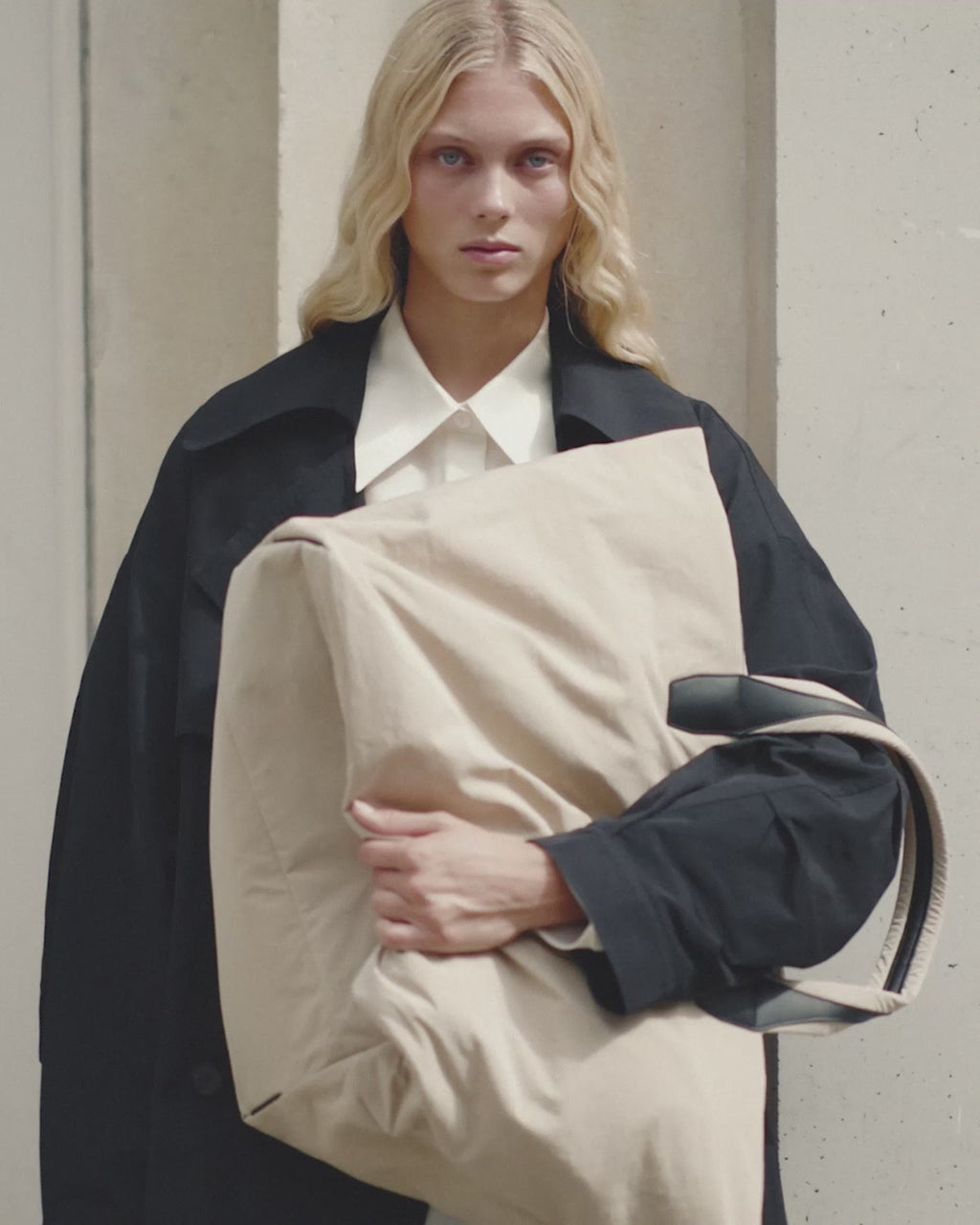 Video of a woman in a black trench coat carrying the Porter Essence Weekender Tote Bag in Beige Trench by Vee Collective.