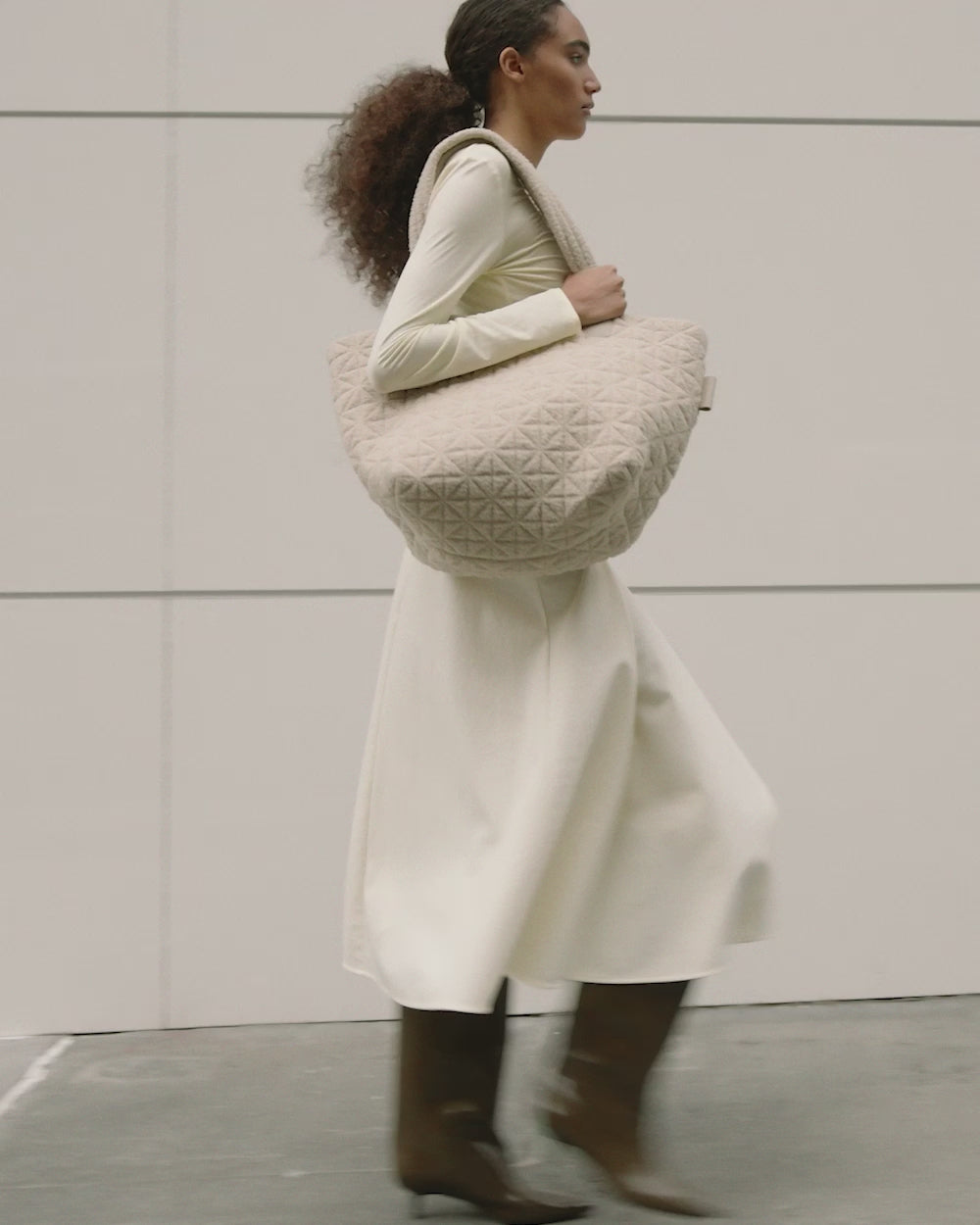 Short clip of a woman walking with the VEE COLLECTIVE Vee Tote Cream Sherpa Medium.