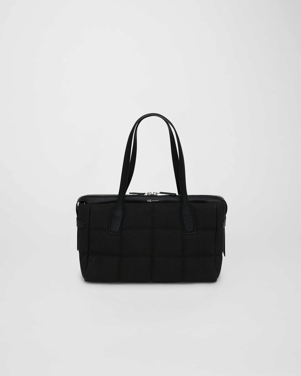 A front-view photo of a Tela Tote featuring matching leather handles and trim, displayed against a plain white background.