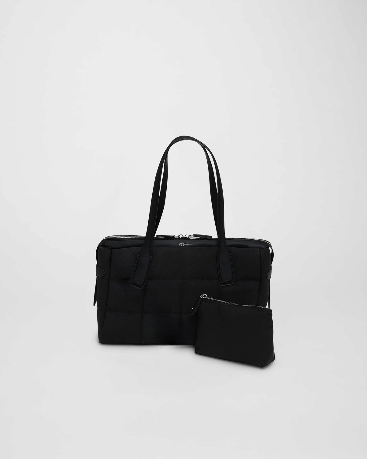A photo of a Tela Tote featuring matching leather handles and trim, paired with a matching pouch, displayed against a plain white background.