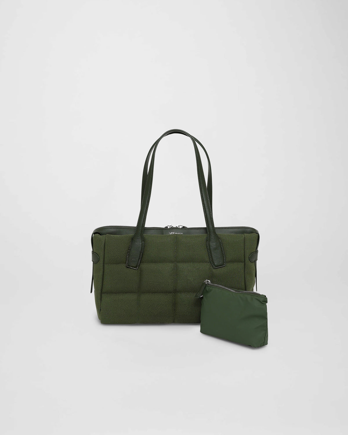 A photo of a Tela Tote featuring matching leather handles and trim, paired with a matching pouch, displayed against a plain white background.