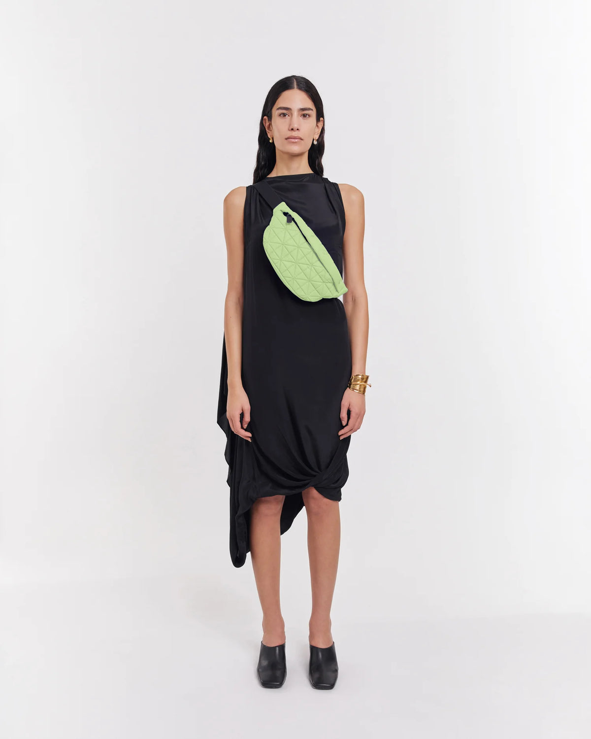 On-body picture of a woman carrying the Vee Fanny Pack in Limelight by Vee Collective, wearing a minimalistic outfit against a clean studio background.