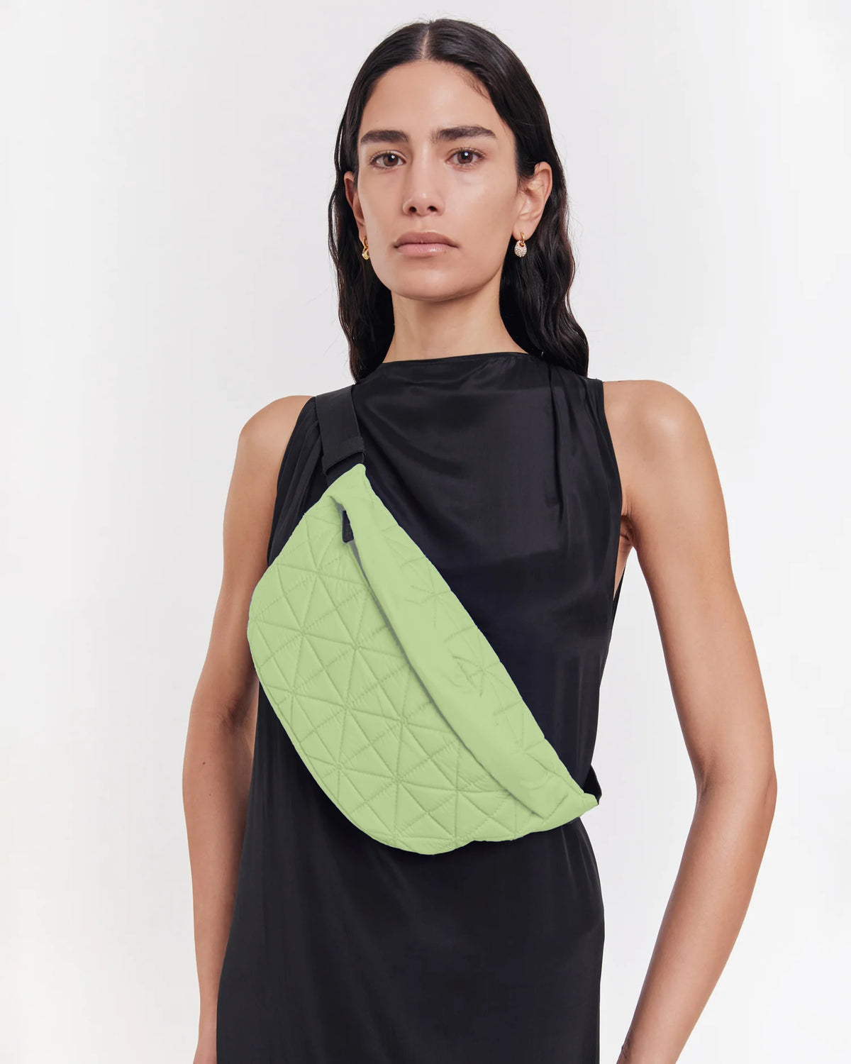 On-body picture of a woman carrying the Vee Fanny Pack in Limelight by Vee Collective, wearing a minimalistic outfit against a clean studio background.