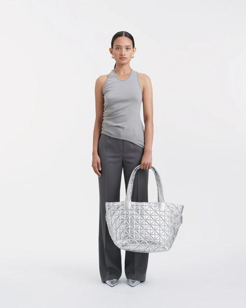 Model holding a large chrome metallic tote with geometric triangular pattern