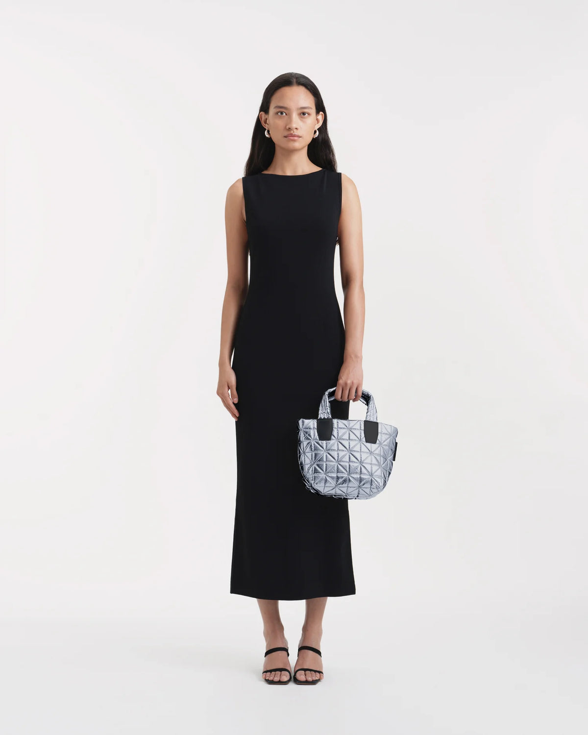 On-body picture of a woman holding the Mini Vee Tote Bag in Icy Silver by Vee Collective, wearing a minimalistic outfit against a clean studio background.