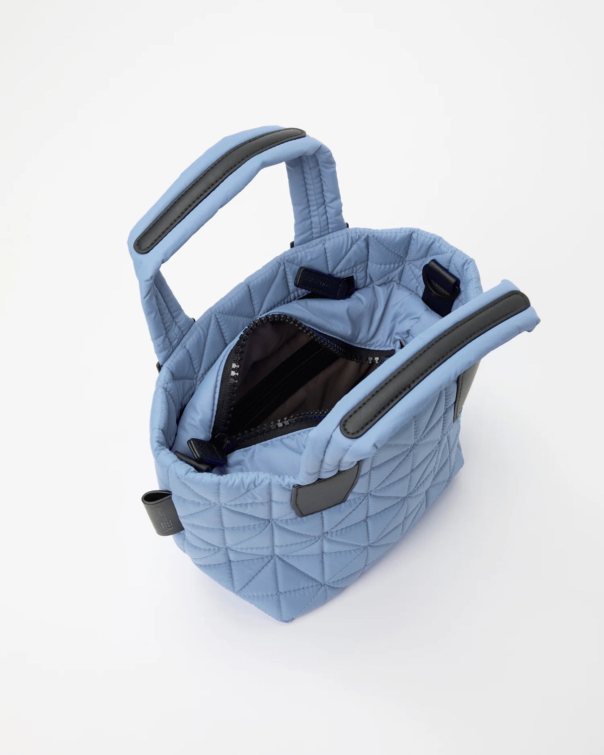 Open Vee Collective Vee Tote Mini in Pigeon Blue, showing the quilted exterior, top zipper, and interior compartments of the tote bag.