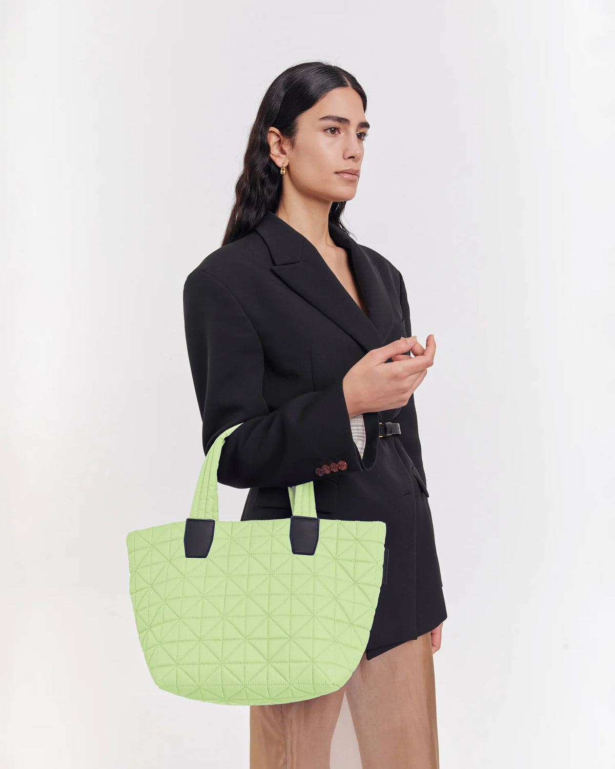 On-body picture of a woman carrying the Small Vee Tote Bag in Limelight by Vee Collective, wearing a minimalistic outfit against a clean studio background.