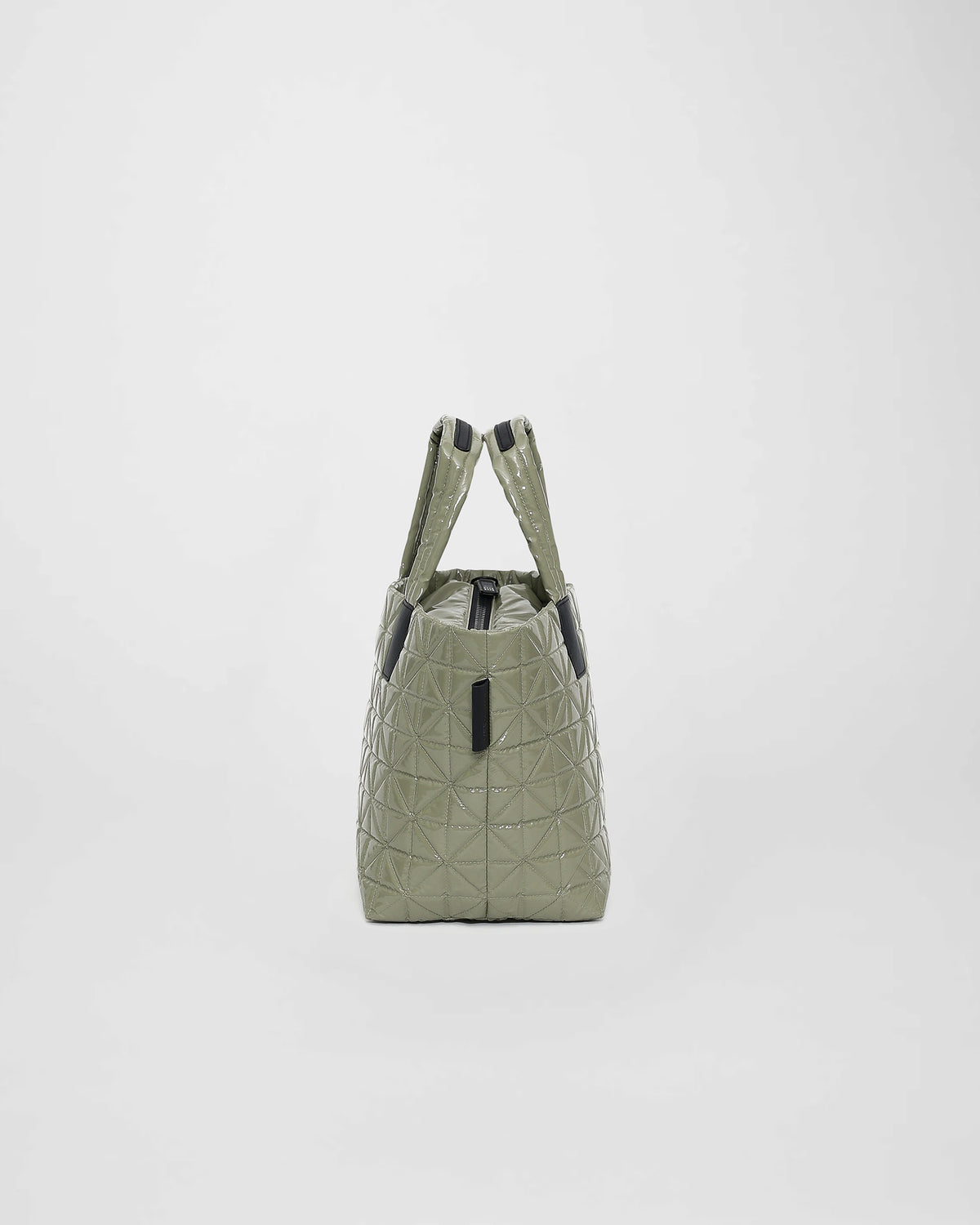 A small sage green tote bag featuring a quilted triangle design and geometric stitching. The bag has two sturdy handles and a zippered top, making it a stylish and versatile accessory for daily use.