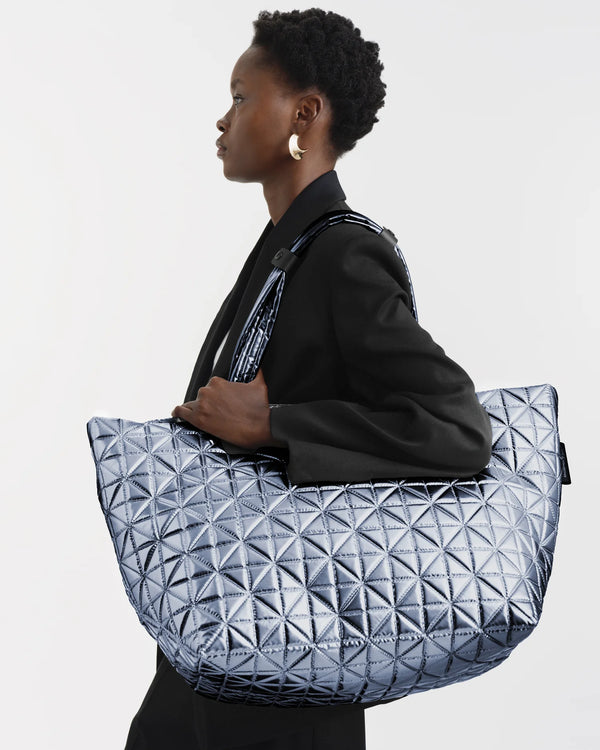On-body picture of a woman carrying the Vee Weekender Tote Bag in Icy Silver by Vee Collective, wearing a minimalistic outfit against a clean studio background.