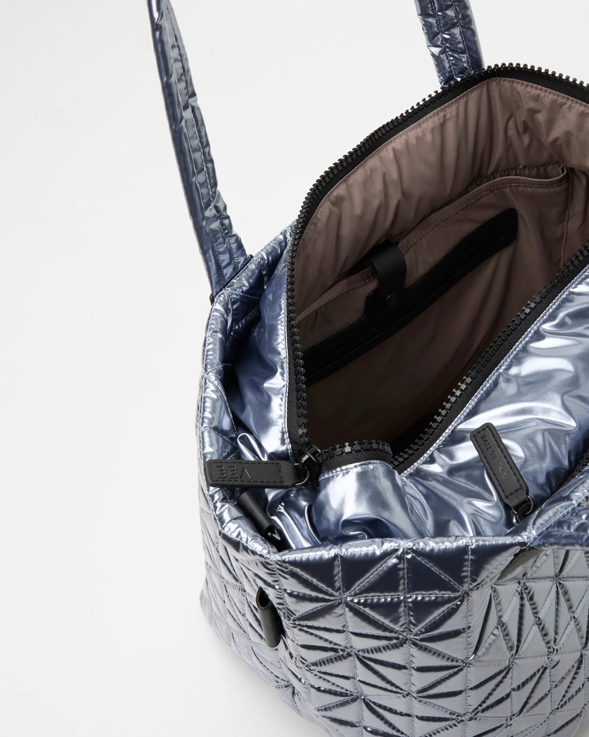 Open Vee Collective Vee Weekender Tote Bag in Icy Silver, showing the quilted exterior, top zipper, and interior compartments of the tote bag.