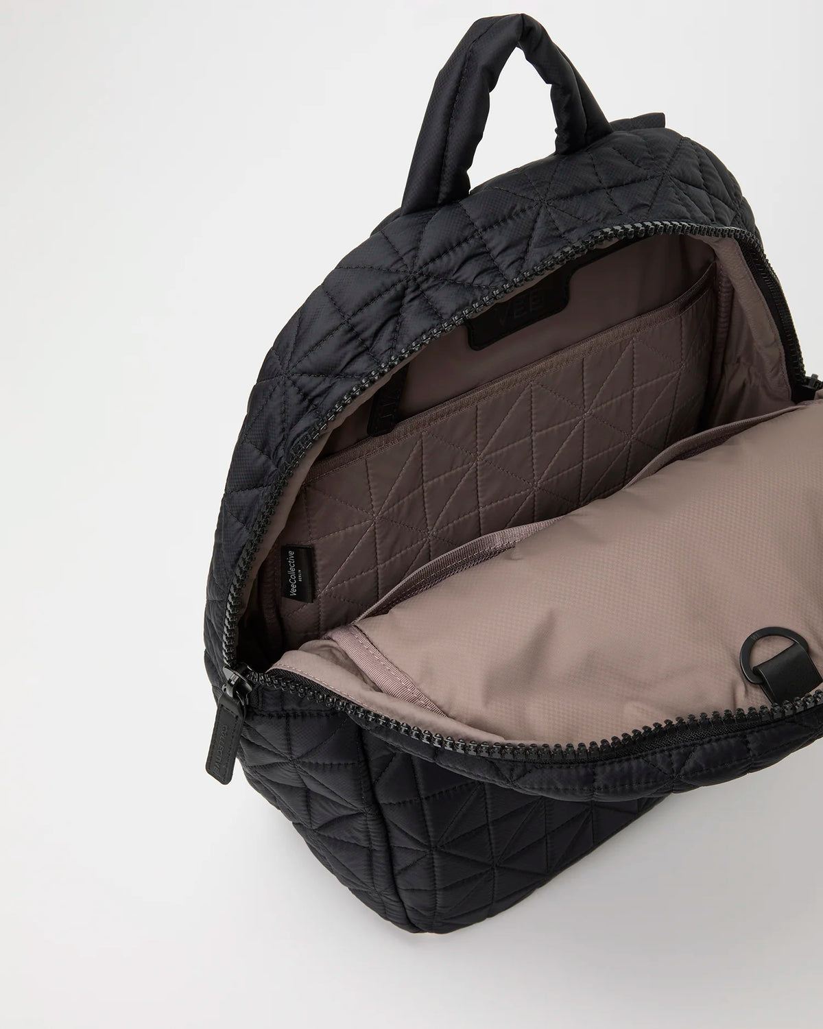 Product photo of the Vee Backpack in matt black, shown slightly angled with the top open to reveal its brown interior lining.